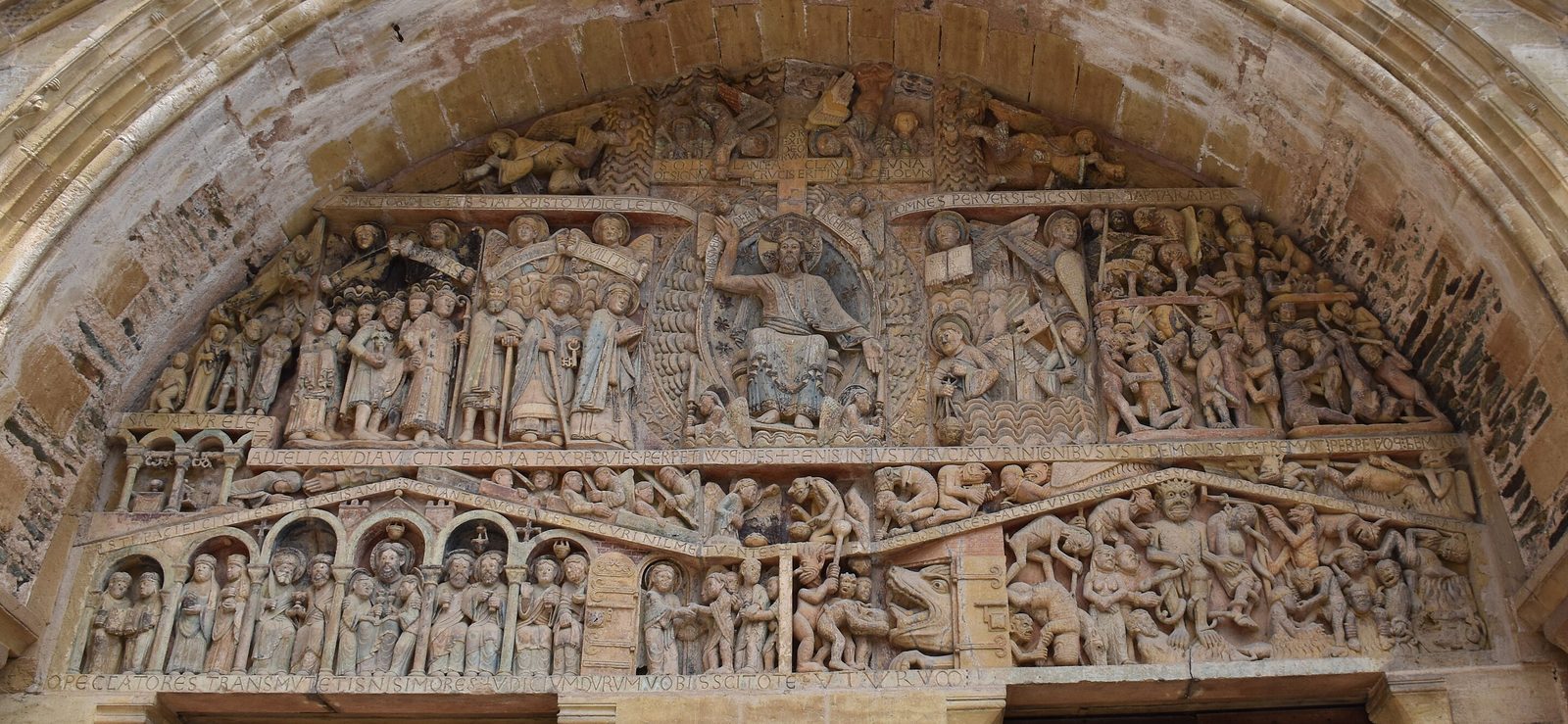 一座罗马式教堂大门上方的半圆形石雕，分成上中下几层，雕满上百个人物。正中一个大的光环里，基督坐着，右手上举，左手下垂；他左边（画面左侧）的人物排成整齐的行列，右边（画面右侧）的人物挣扎扭打。最下层左边是一排拱廊，右边是一张怪兽的大嘴和一群受折磨的人。最底下一条长石带刻满拉丁字母。石头上残留着淡蓝、淡红的颜色。