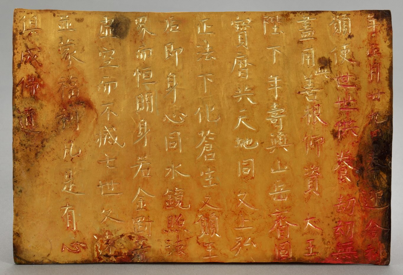同一块金板的另一面：竖行的汉字只在右边几行填着红色，其余是金色的刻痕。最右一行可以读出“年正月廿九日奉迎舍利”。