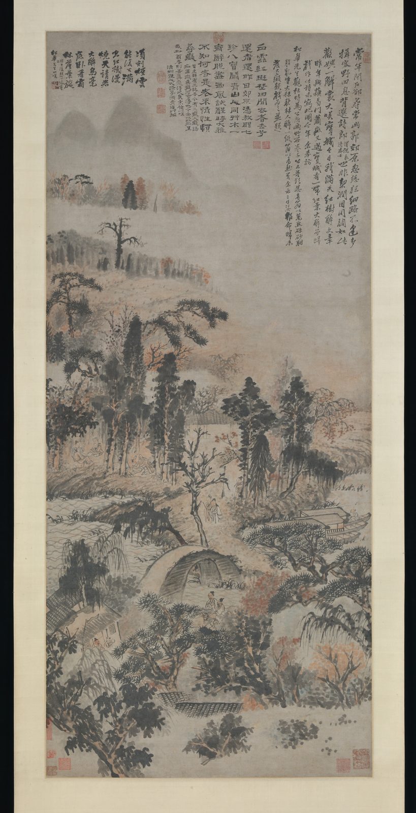 一幅装裱好的立轴：秋天的山林里，红、褐、墨色的树叶一团团交错，几座山头在雾中若隐若现，树下有几个小小的人和一座小桥；画面上方有三段密密的题字，字体大小、墨色各不相同。