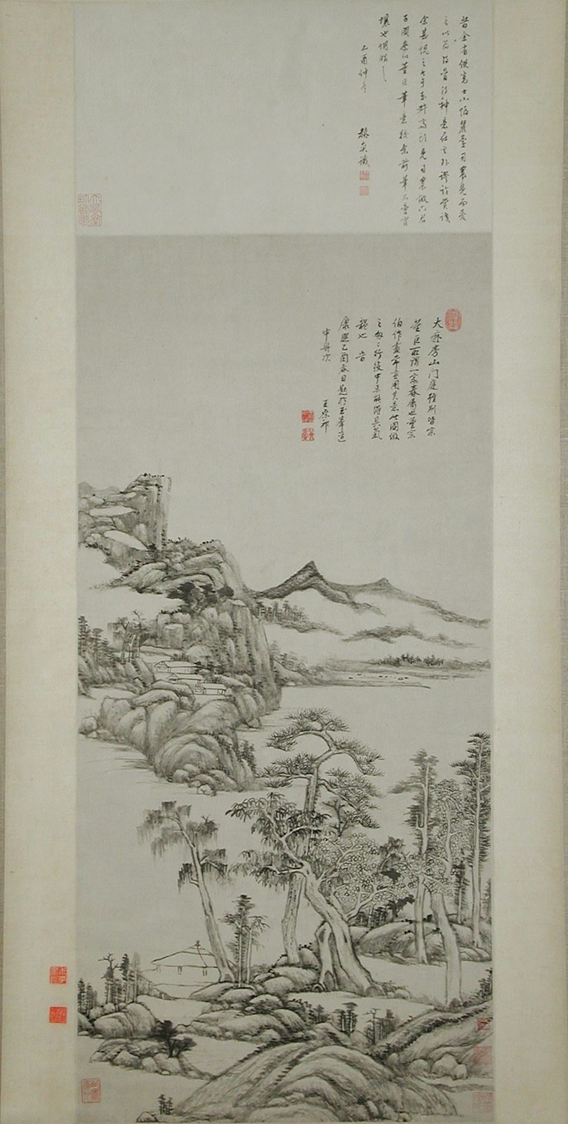 一幅装裱好的水墨立轴：画面下半部是层层叠叠的山坡、树丛和水边的小屋，用淡墨和干笔皴擦，结构像一块块堆起的积木；上半部是大片空白和几段题字。